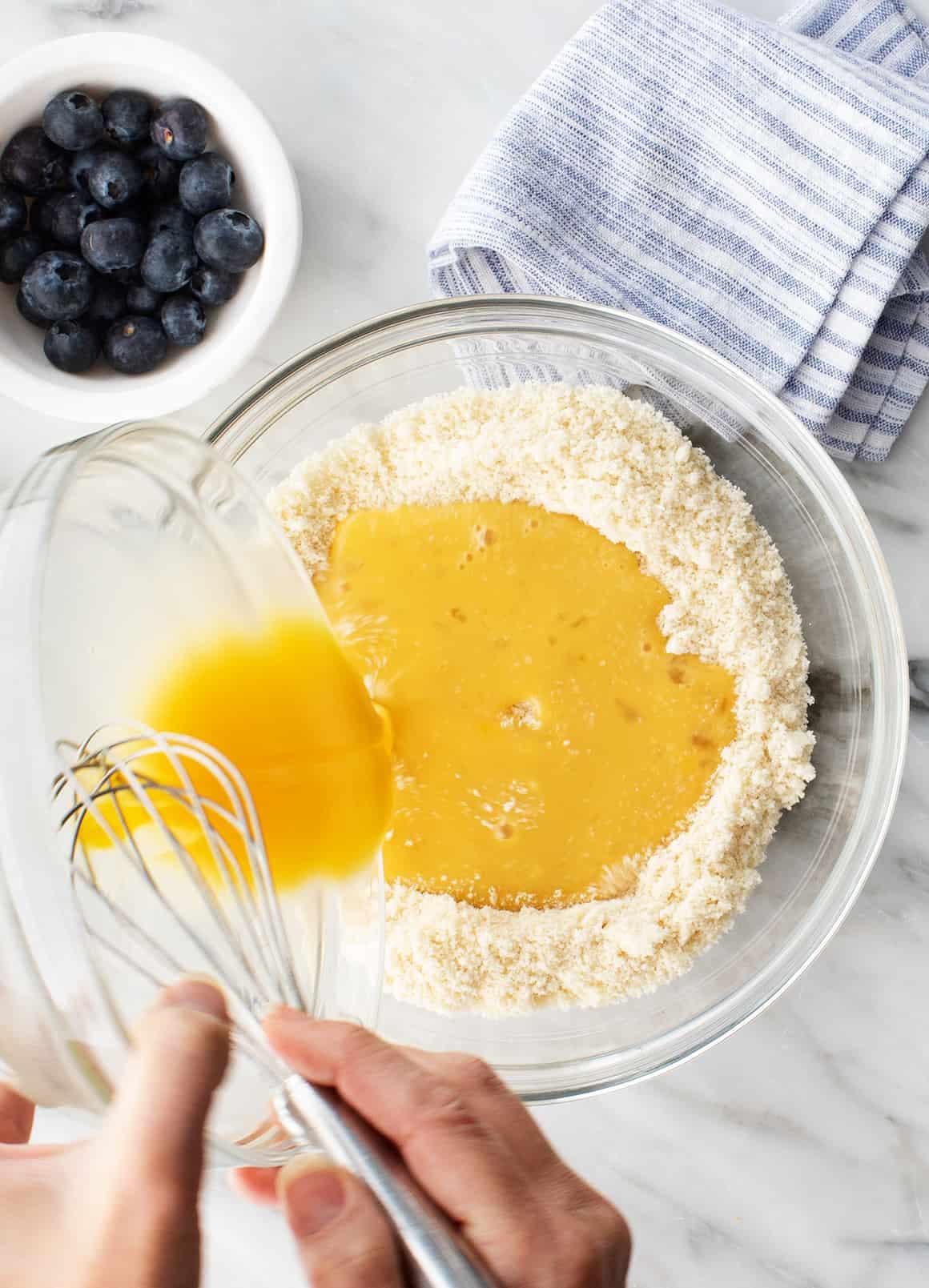 Pouring wet ingredients into bowl of dry ingredients