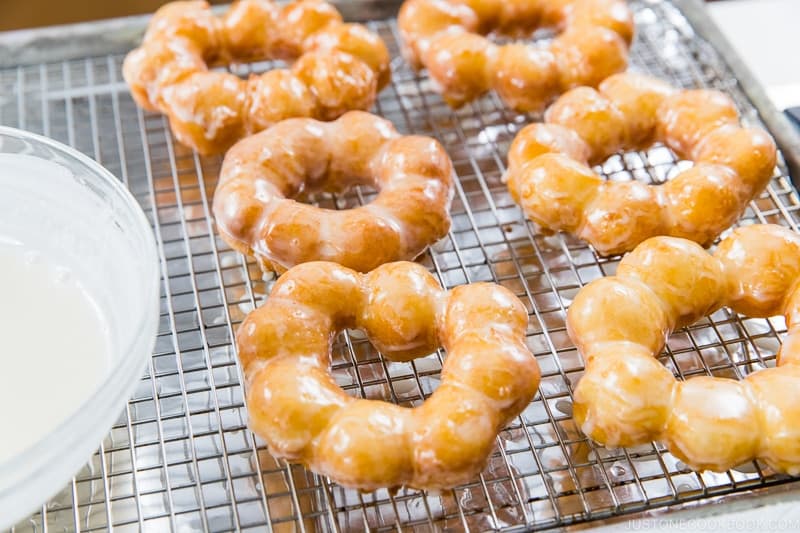 Place the glazed donuts onto the prepared rack to allow the excess glaze to drip down. The glaze will set and harden on the donuts after 30 minutes.