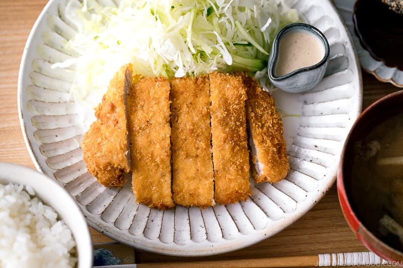 Transfer to a plate and serve it with the shredded cabbage and cucumber, the sesame dressing in small individual cups, and the sesame tonkatsu dipping sauce on the side.