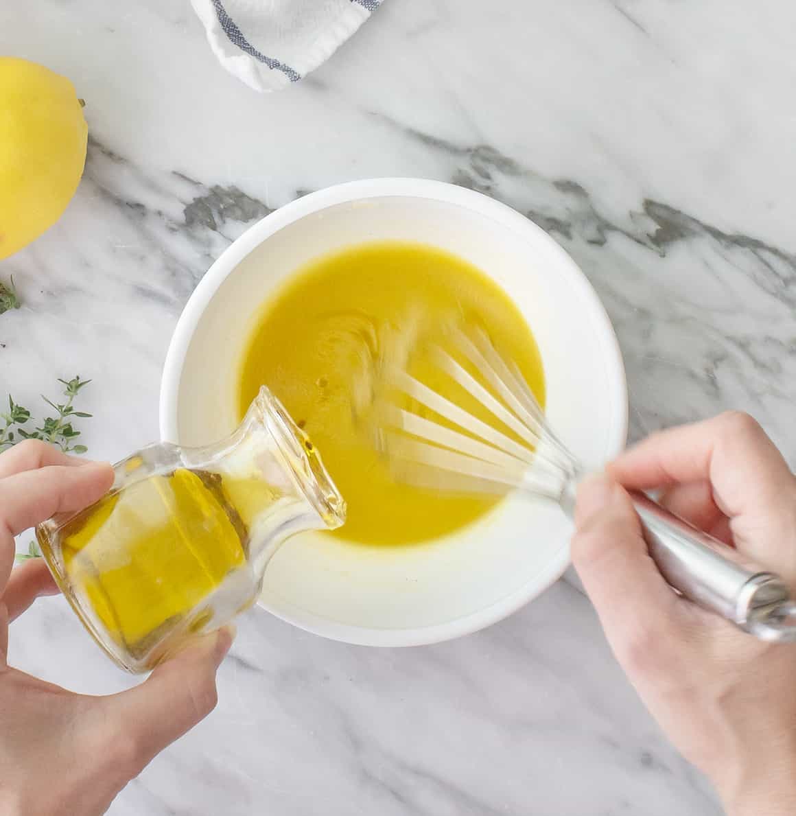 Whisking olive oil into lemon vinaigrette dressing