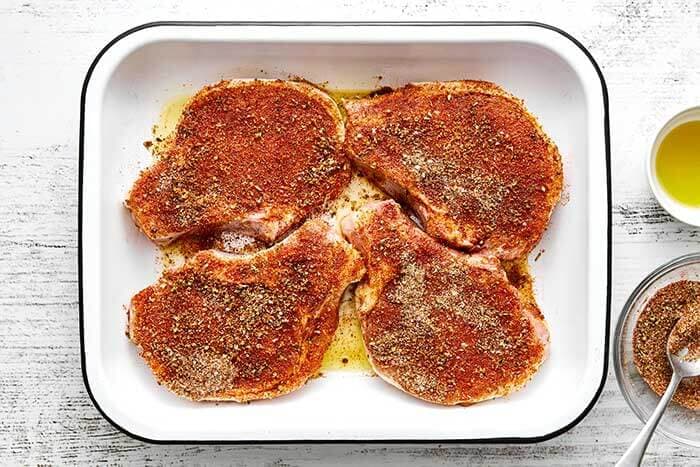 Season the pork chops. Place the pork chops in a baking dish or on a rimmed baking sheet. Drizzle the olive oil on both sides and sprinkle the seasoning on both sides, then rub it in.