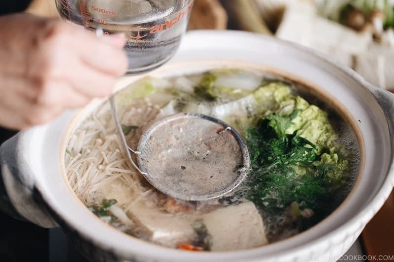 Skim off the scum and foam from the surface, especially after cooking the meat, to keep the broth as clean as possible. Then, add the softer, leafy vegetables to the broth as you make room in the pot. Simmer for a few minutes and serve. Cook the meat as you're ready to eat, and enjoy the other ingredients while restocking the pot along the way.Tip: Prepare a fine-mesh skimmer and a 2-cup measuring cup filled with water so you can easily skim as you cook at the table.